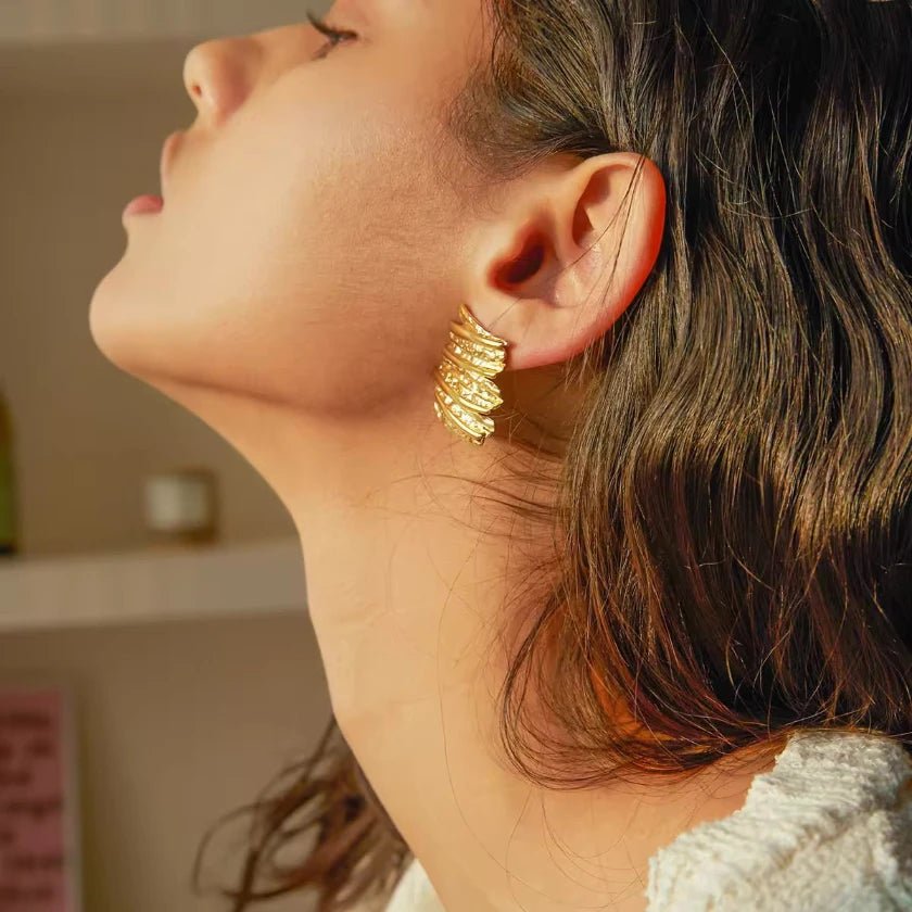 Goldene Vintage-Ohrstecker mit strukturierter, wellenförmiger Oberfläche im Antik-Look.