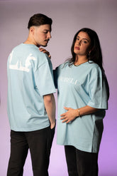 Produktansicht des hellblauen Oversize Unisex T-Shirts, die sowohl die Vorderseite mit dem weißen 'LOURELL'-Schriftzug als auch die Rückseite mit dem großen, weißen Engel-Logo-Print zeigt.