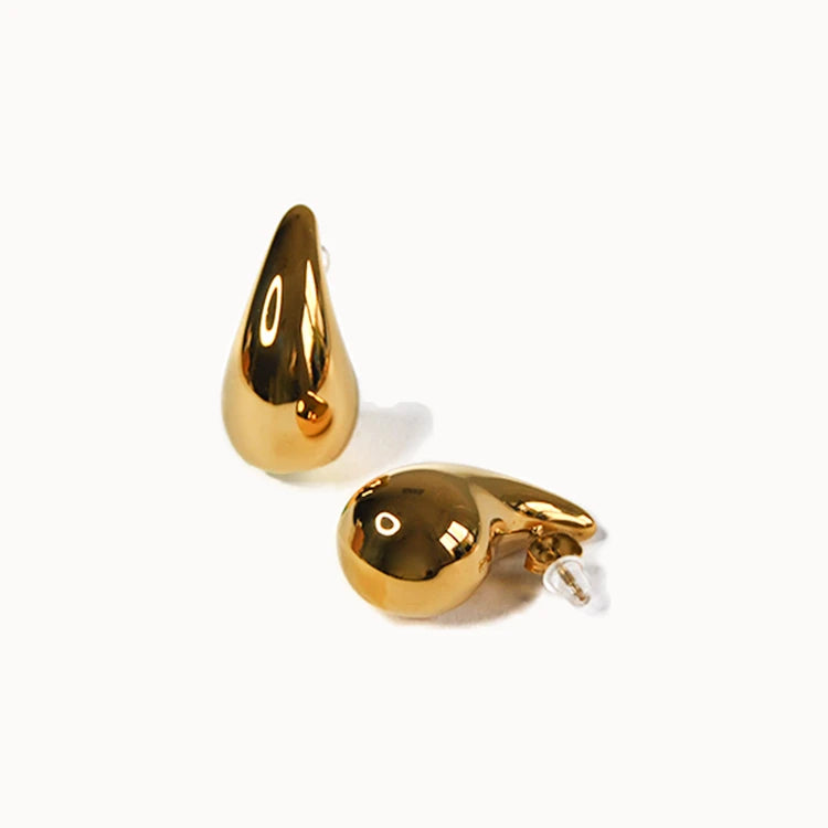 Paar goldene Ohrstecker in einer voluminösen, glatten Tropfenform, die sich nach oben hin verjüngt und stark glänzt.