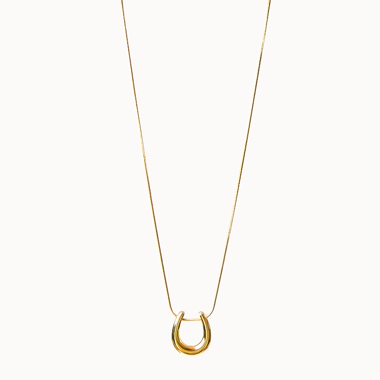 Feine Halskette in Gold, an der ein glänzender, gebogener Loop-Anhänger gleitet.