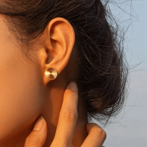 Runde Plättchen-Ohrstecker in Gold mit strahlenförmig geriffelter Oberfläche.