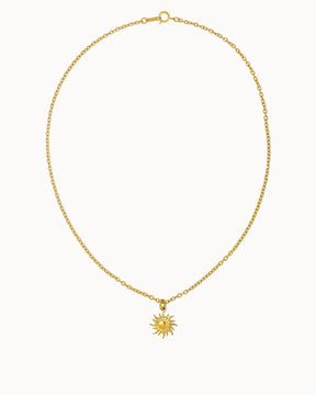 Feine Gliederkette in Gold, an der ein runder Anhänger in Form einer Sonne mit geschwungenen Strahlen hängt.