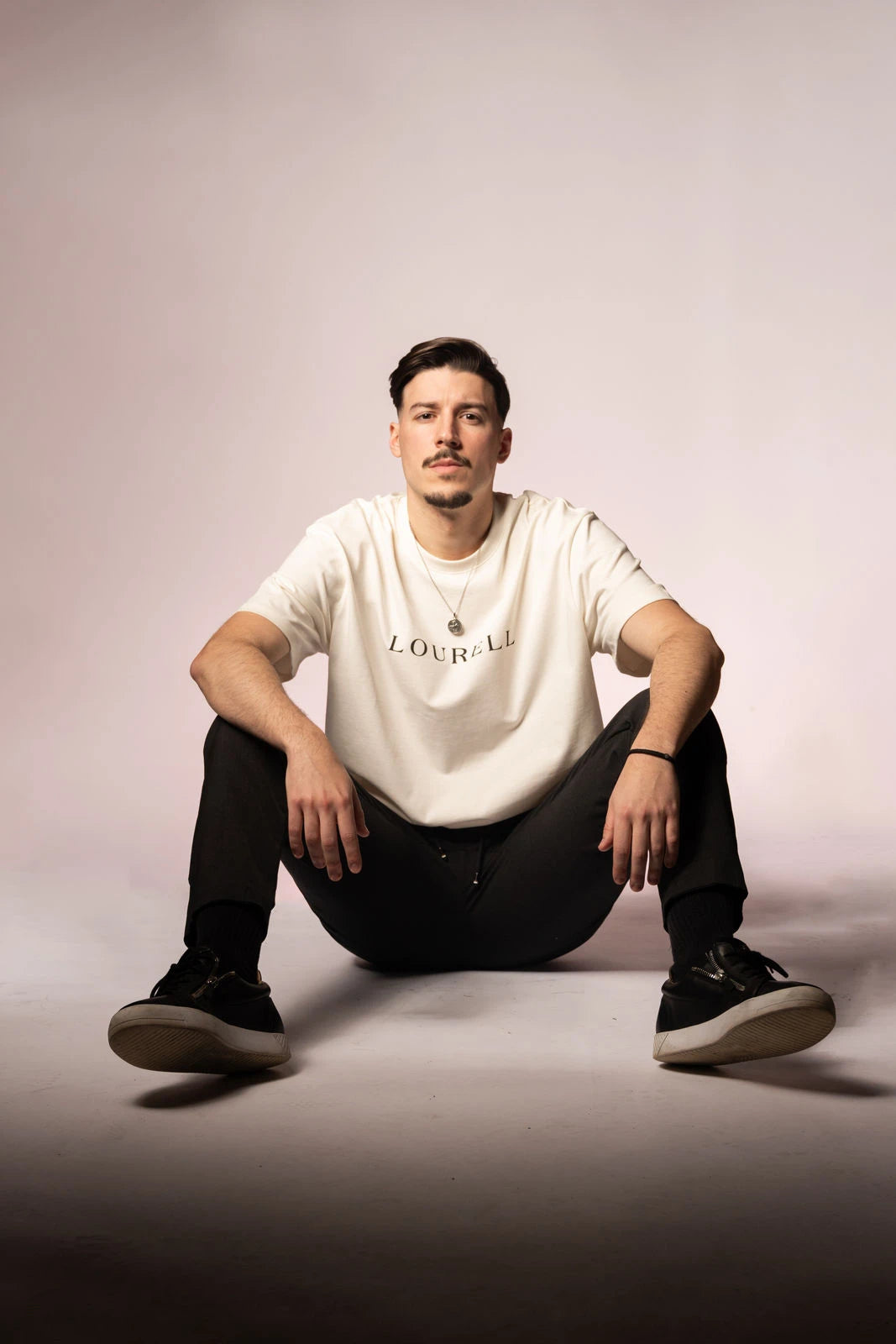 Weißes Oversize T-Shirt aus 100% Baumwolle mit großem, zentriertem 'LOURELL' Schriftzug in Schwarz auf der Brust.