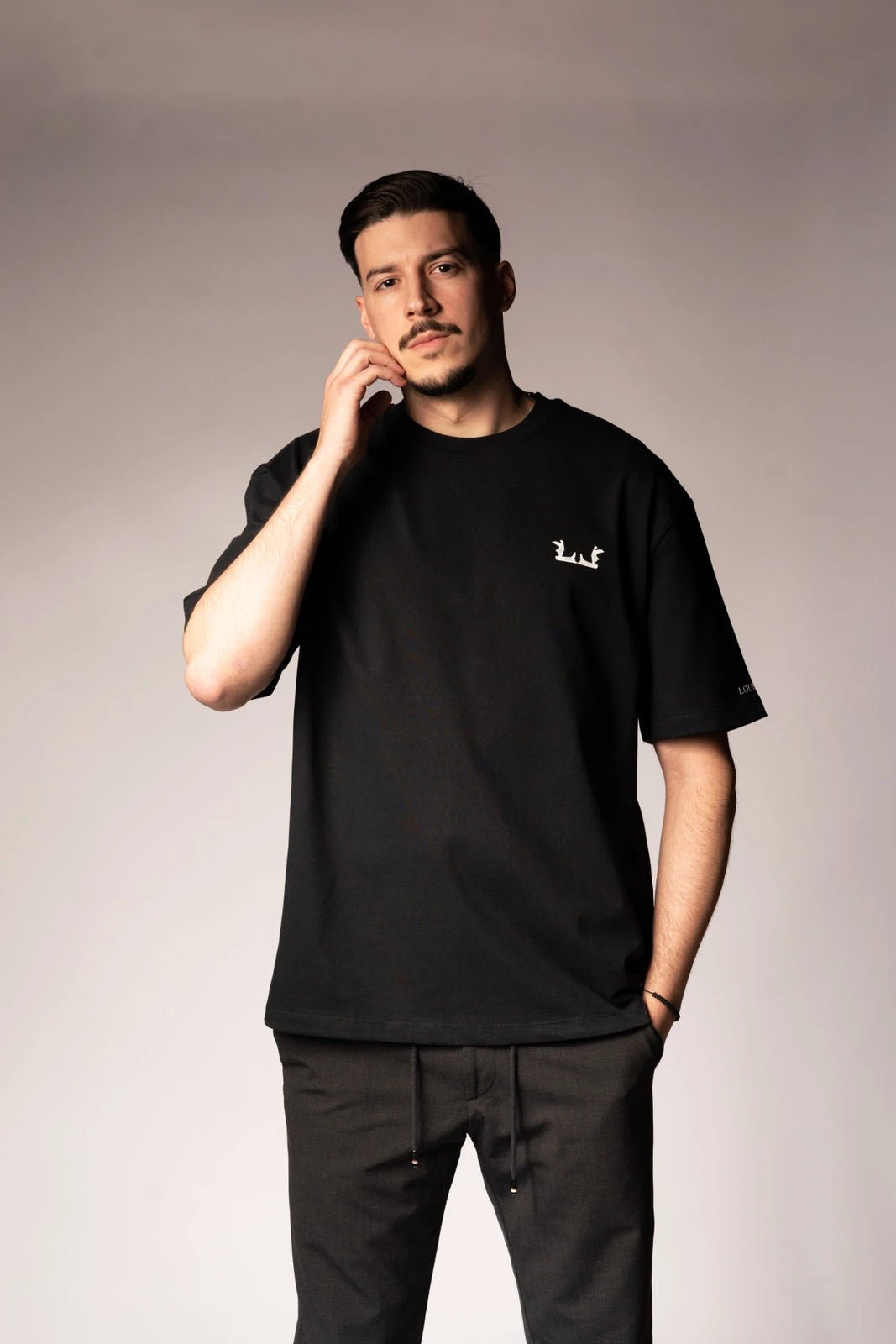 Schwarzes Oversize T-Shirt mit weißem Logo auf der Brust und Lourell-Schriftzug am Ärmel.