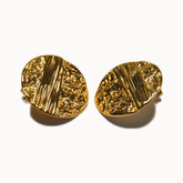 Große goldene Statement-Ohrstecker mit unregelmäßiger, gehämmerter Oberfläche und organischem Relief-Design.