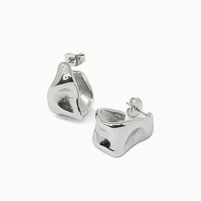 Moderne Creolen in Silber mit einer einzigartigen, unregelmäßig geformten und wellenförmigen Oberfläche.
