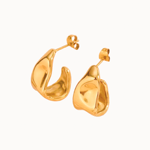 Elegante Creolen in Gold mit einer modernen, skulpturalen Silhouette und fließender Metall-Optik.