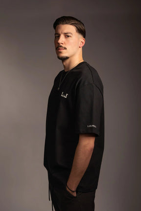 Schwarzes Oversize T-Shirt mit weißem Logo auf der Brust und Lourell-Schriftzug am Ärmel.