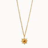 Feine Gliederkette in Gold, an der ein runder Anhänger in Form einer Sonne mit geschwungenen Strahlen hängt.