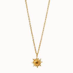 Feine Gliederkette in Gold, an der ein runder Anhänger in Form einer Sonne mit geschwungenen Strahlen hängt.