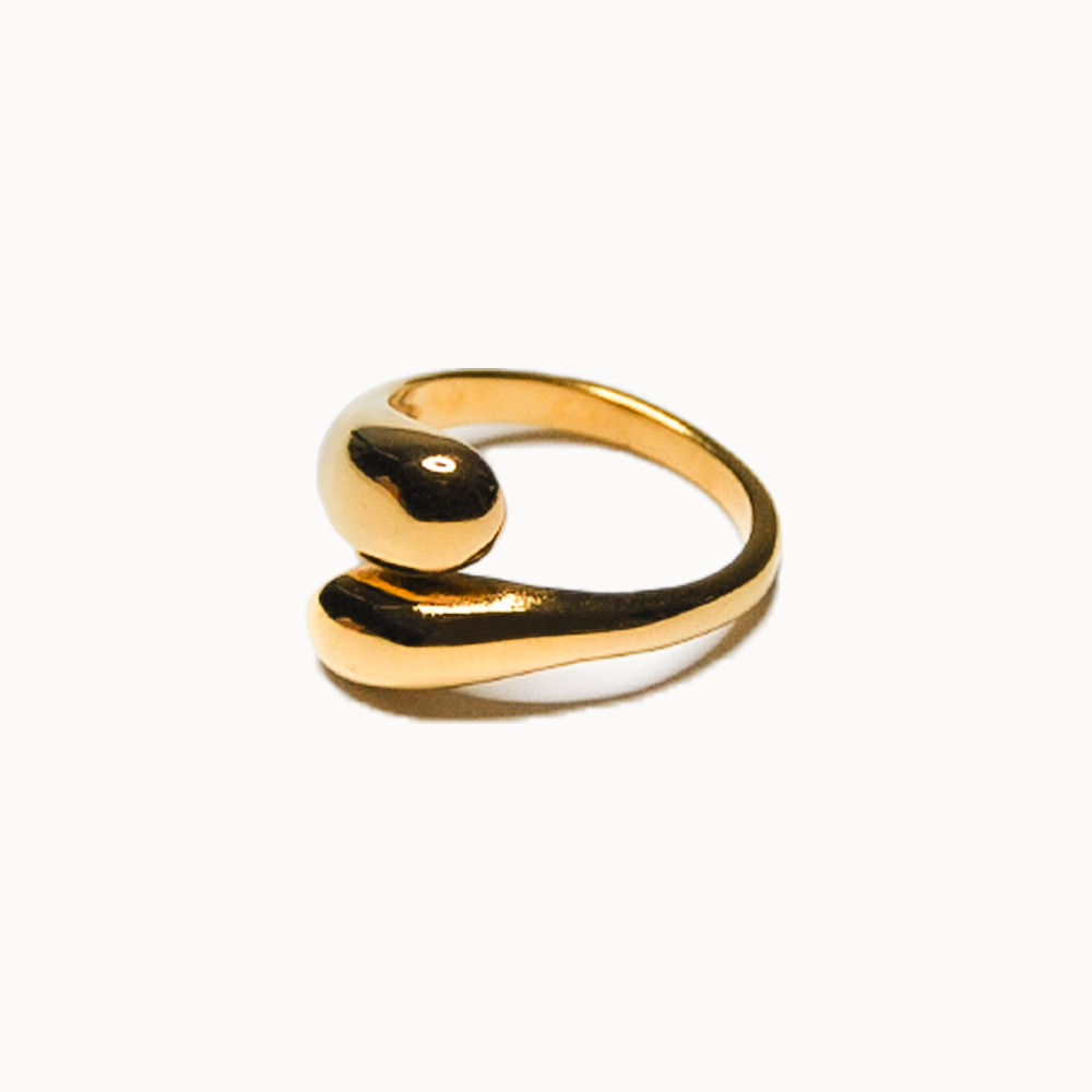 Offener Ring in Gold, dessen Enden zu dicken, geschwungenen Tropfen geformt sind, die an der Oberseite aneinander vorbeigleiten.