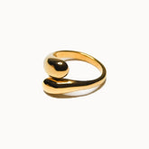 Offener Ring in Gold, dessen Enden zu dicken, geschwungenen Tropfen geformt sind, die an der Oberseite aneinander vorbeigleiten.