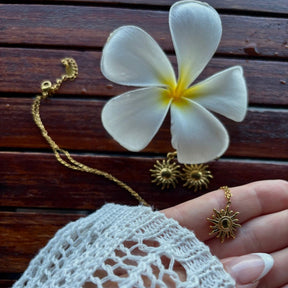 Schmuck-Duo in Gold: Eine feine Gliederkette mit großem Sonnen-Motiv und dazu passende kleine Creolen mit hängenden Sonnen.