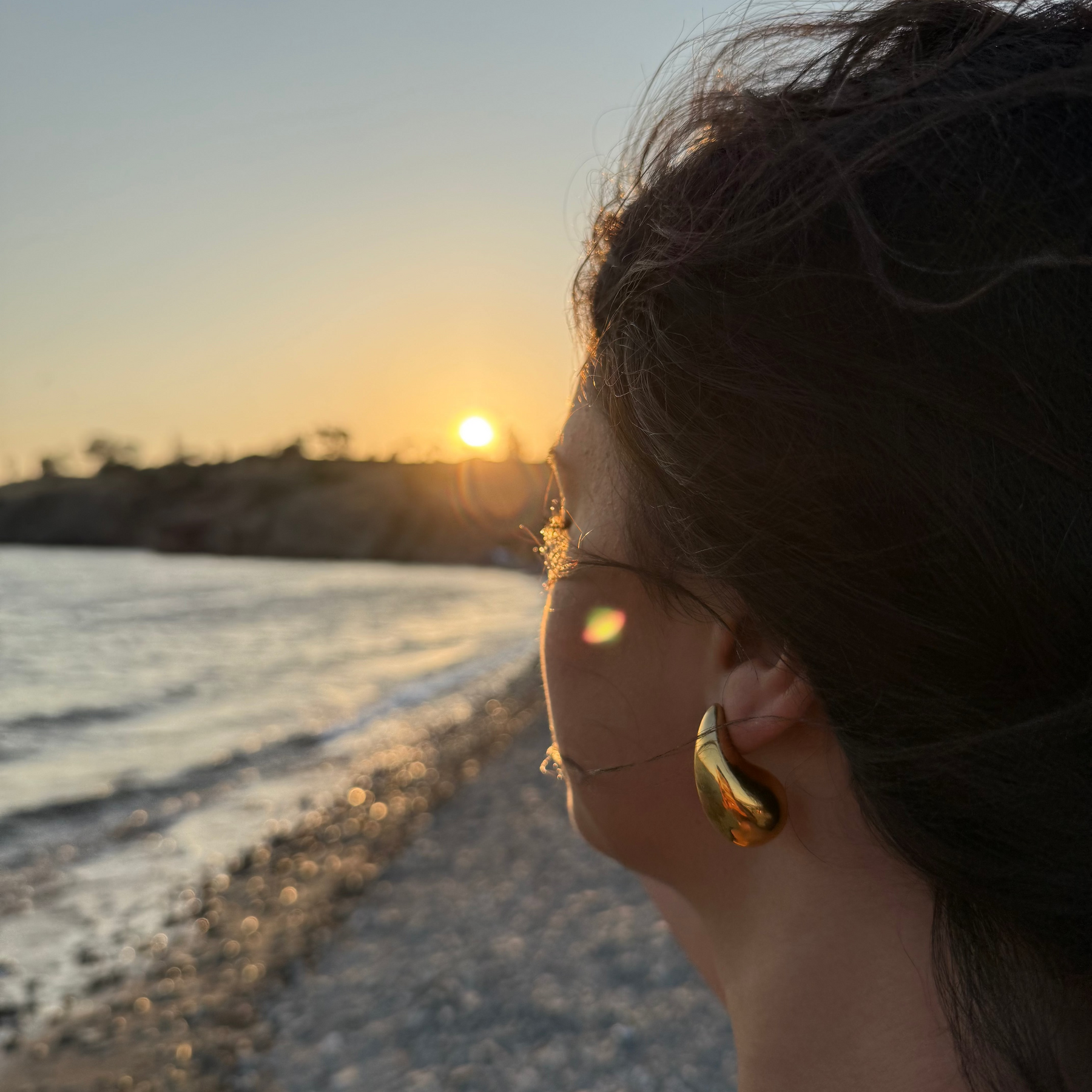 Paar goldene Ohrstecker in einer voluminösen, glatten Tropfenform, die sich nach oben hin verjüngt und stark glänzt.