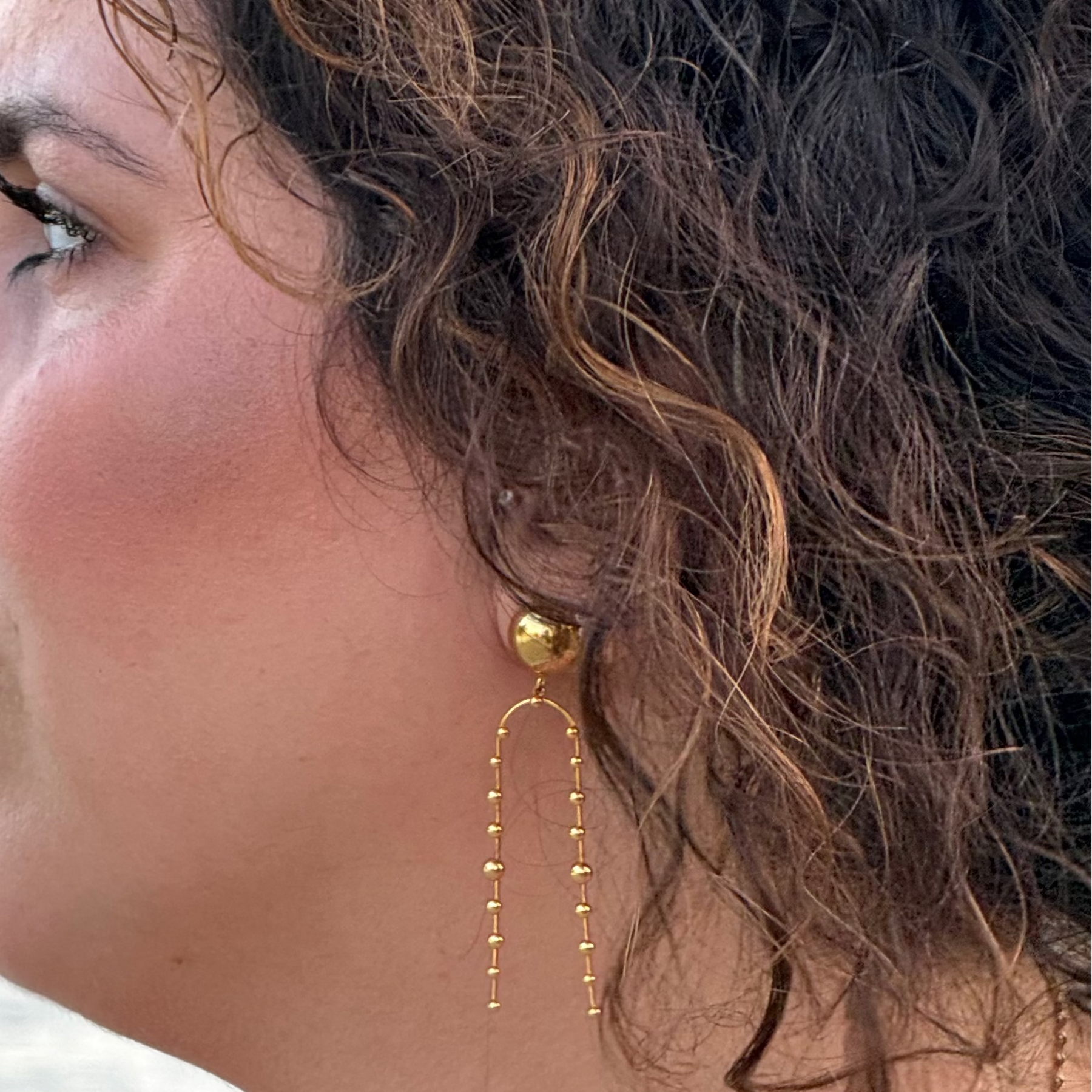 Goldene Statement-Ohrhänger mit großer Kugel und langen, feinen Kugelketten.