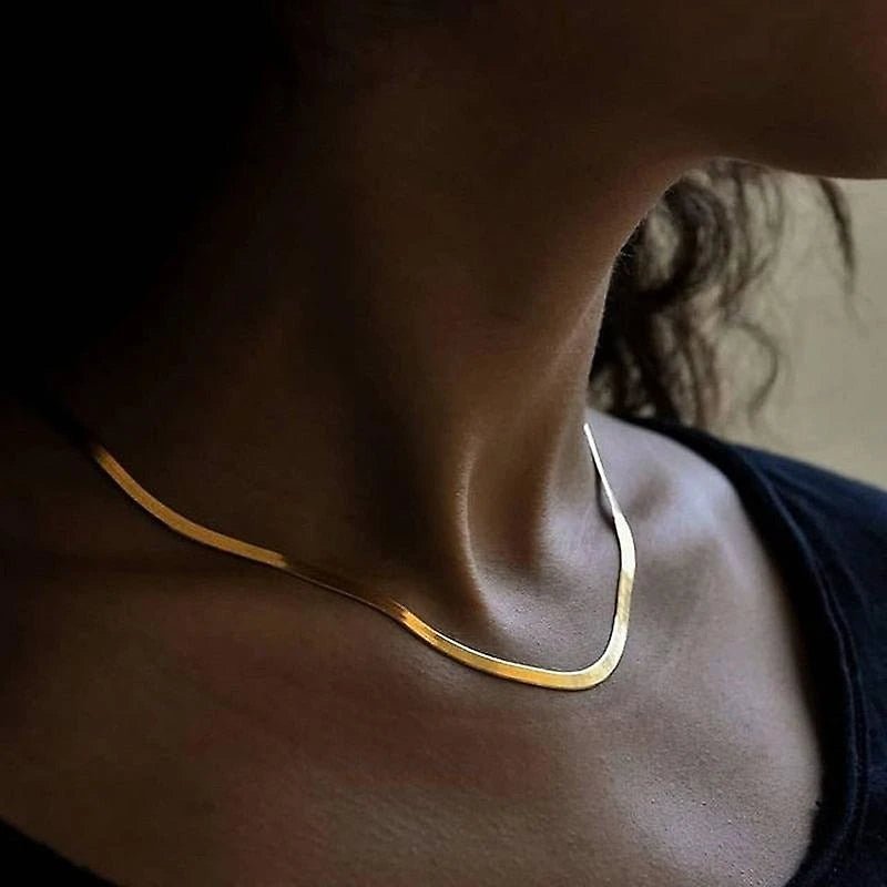 Breite, flach aufliegende Goldkette mit feiner Struktur, die wie eine flüssige goldene Linie wirkt.