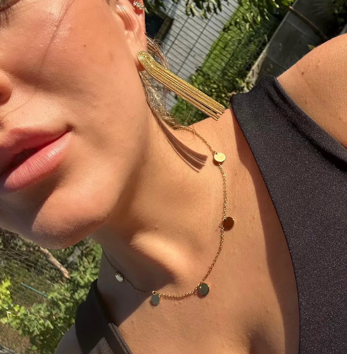 String Drop Ohrringe und goldene Halsketten im Tageslicht